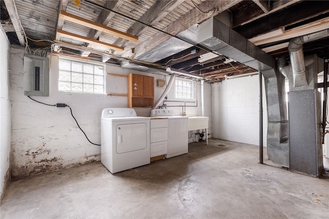 below grade area with heating unit, electric panel, separate washer and dryer, and a sink