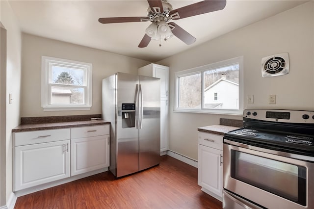 kitchen featuring dark countertops, visible vents, appliances with stainless steel finishes, white cabinetry, and wood finished floors