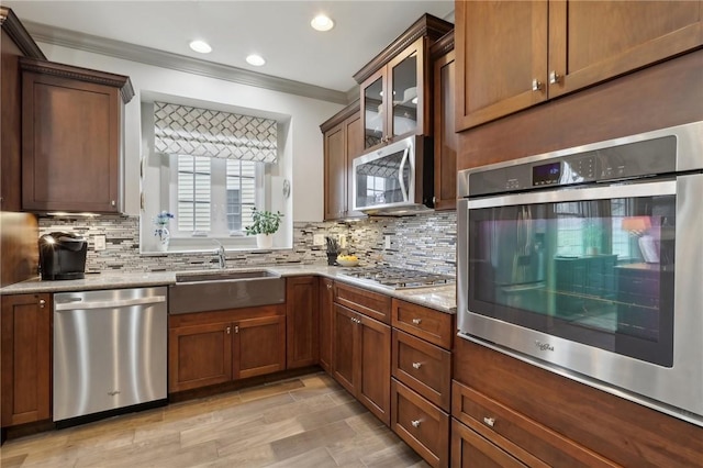 kitchen featuring a sink, stainless steel appliances, decorative backsplash, and crown molding