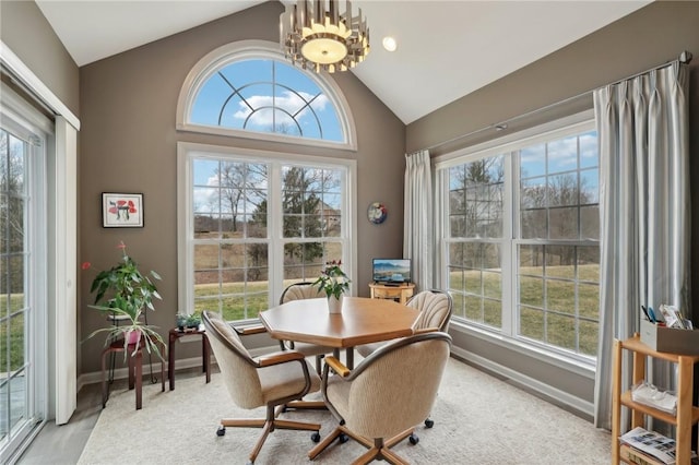 dining room with an inviting chandelier, a healthy amount of sunlight, baseboards, and lofted ceiling