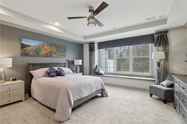 bedroom with a tray ceiling, visible vents, baseboards, and carpet flooring