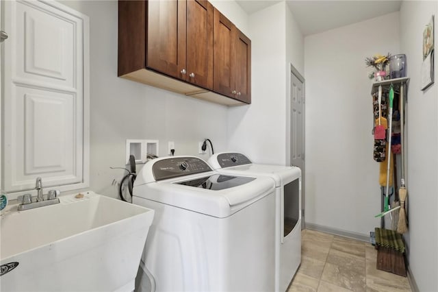 clothes washing area with washing machine and clothes dryer, cabinet space, baseboards, and a sink