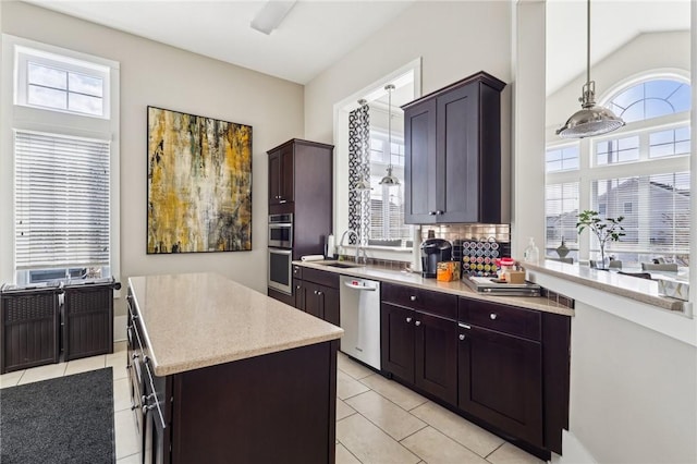 kitchen featuring a kitchen island, a sink, decorative backsplash, hanging light fixtures, and appliances with stainless steel finishes