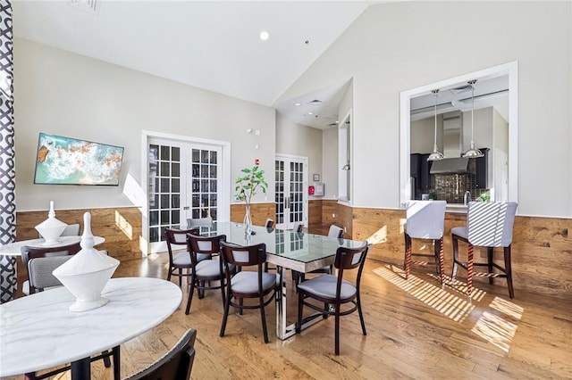 dining room featuring wainscoting, french doors, high vaulted ceiling, and wood finished floors