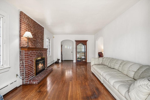 living room featuring a brick fireplace, a baseboard radiator, arched walkways, and wood-type flooring