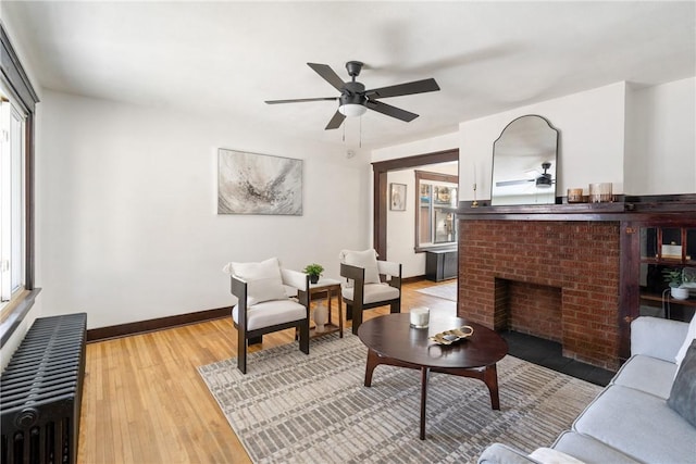 living area featuring light wood-style floors, radiator heating unit, ceiling fan, and a wealth of natural light