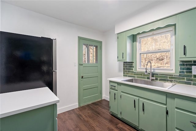 kitchen featuring a sink, green cabinets, light countertops, backsplash, and freestanding refrigerator