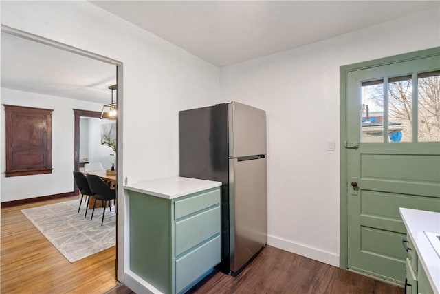 kitchen with dark wood-style floors, light countertops, freestanding refrigerator, and baseboards