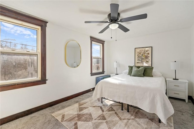 carpeted bedroom with radiator heating unit, baseboards, and a ceiling fan