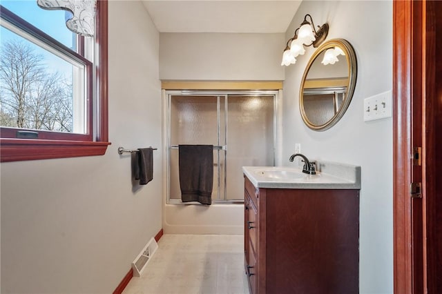 bathroom featuring bath / shower combo with glass door, vanity, visible vents, baseboards, and tile patterned floors