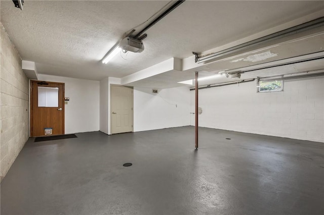 garage featuring a garage door opener and concrete block wall