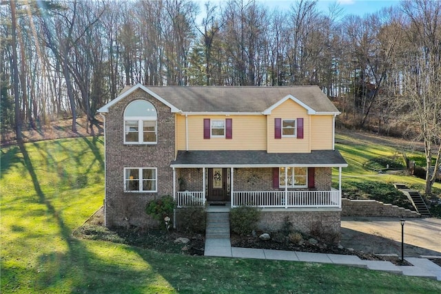 view of front of property featuring covered porch, brick siding, and a front yard