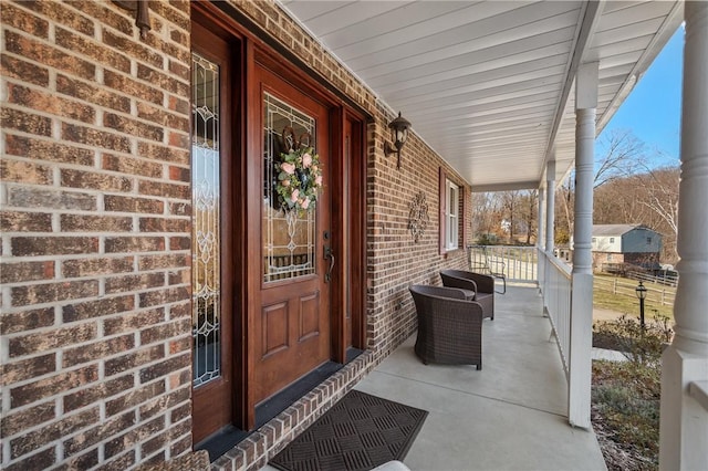 property entrance featuring a porch and brick siding