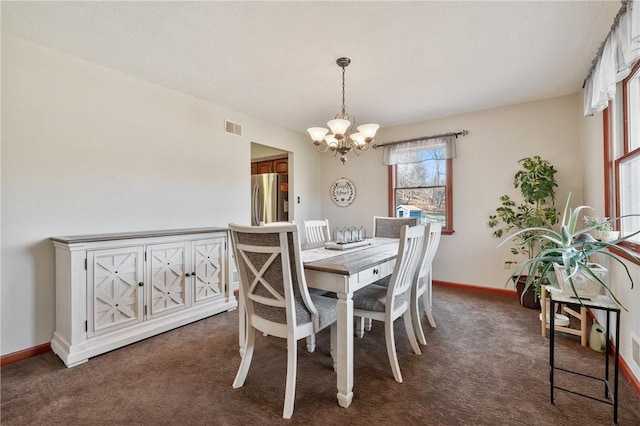 dining area featuring baseboards, visible vents, dark colored carpet, and a chandelier