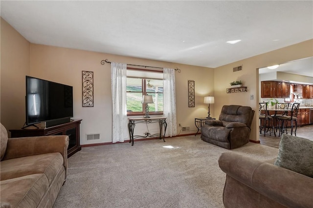 living room with baseboards, visible vents, and light colored carpet