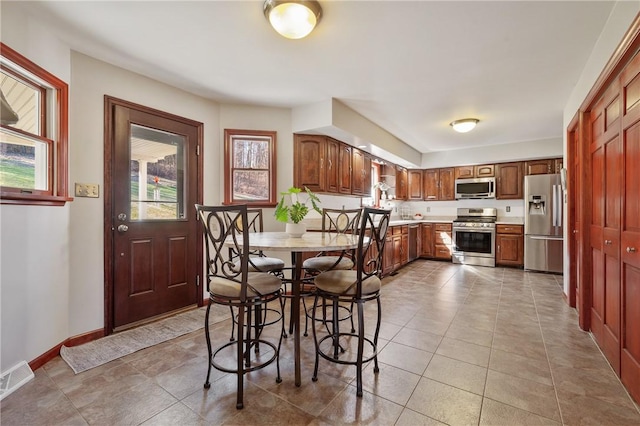 kitchen featuring baseboards, brown cabinetry, visible vents, stainless steel appliances, and light countertops