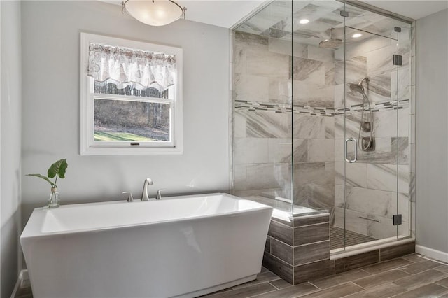 bathroom with a freestanding bath, wood finish floors, a stall shower, and baseboards