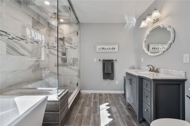 full bath featuring wood finish floors, a shower stall, vanity, a tub, and baseboards