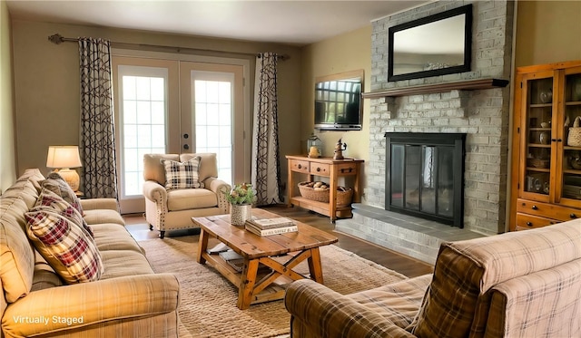 living room with french doors, a brick fireplace, and wood finished floors