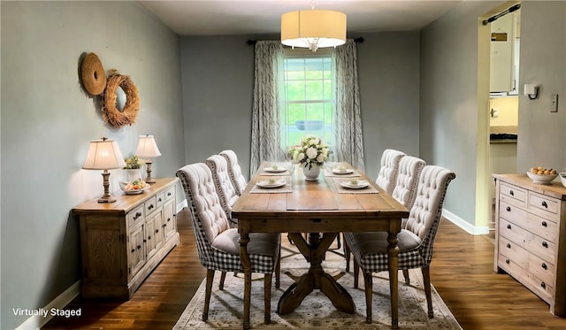 dining space featuring dark wood-type flooring and baseboards
