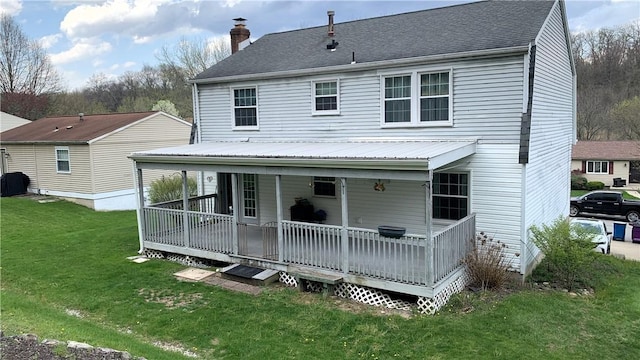 back of property with a lawn, a chimney, and metal roof