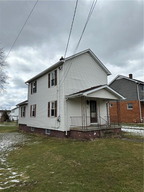 rear view of house featuring covered porch and a lawn