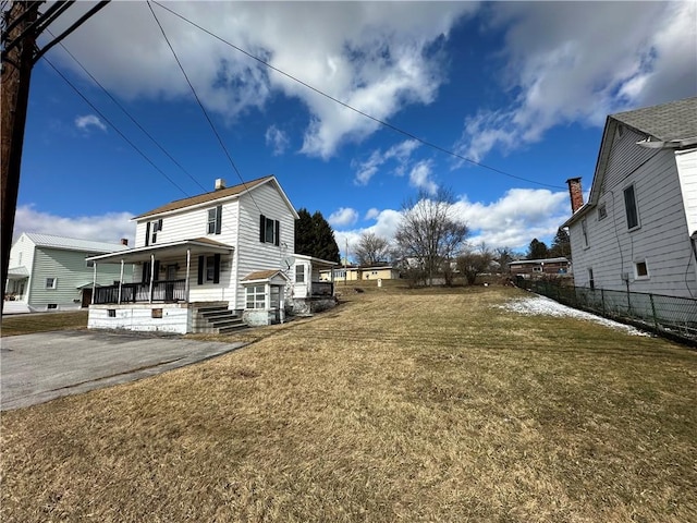 view of home's exterior with a yard, a porch, and fence