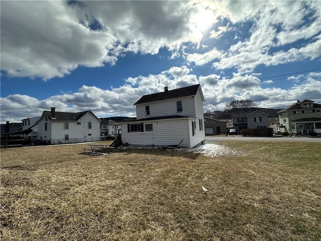 rear view of house with a residential view, fence, and a lawn