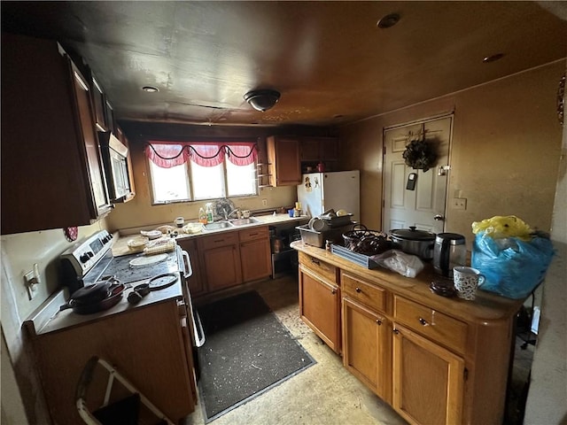 kitchen with brown cabinets, stainless steel microwave, freestanding refrigerator, a sink, and butcher block countertops