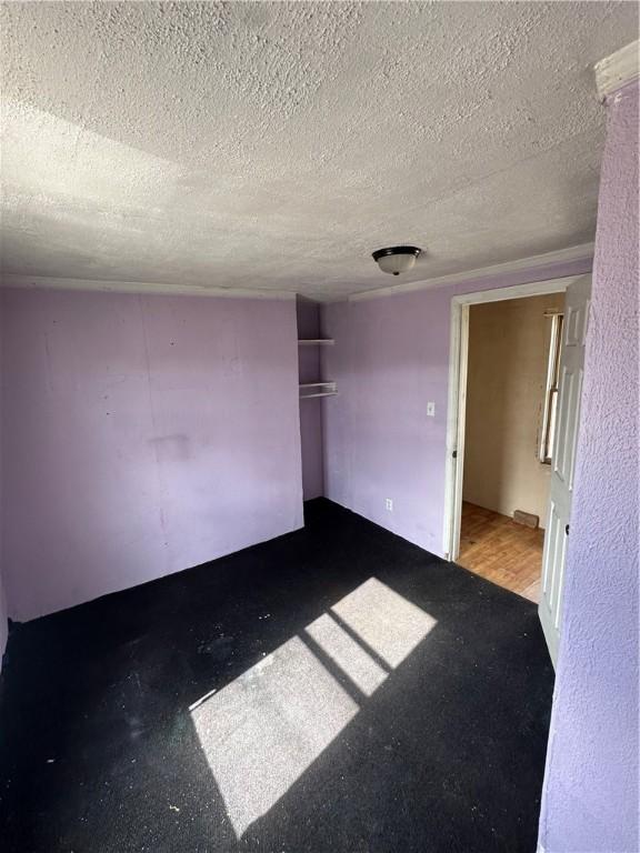 unfurnished room with concrete flooring and a textured ceiling