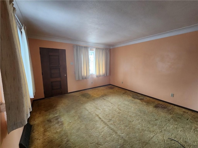 carpeted empty room with baseboards, a textured ceiling, and ornamental molding