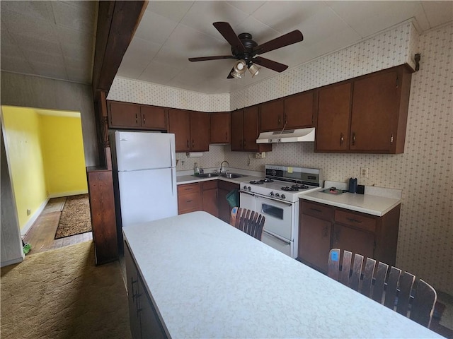 kitchen featuring under cabinet range hood, white appliances, light countertops, and wallpapered walls