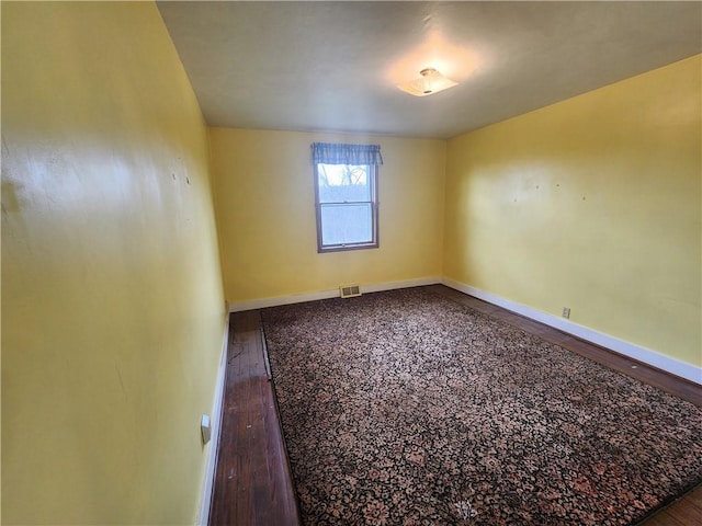 unfurnished room with baseboards and dark wood-style flooring