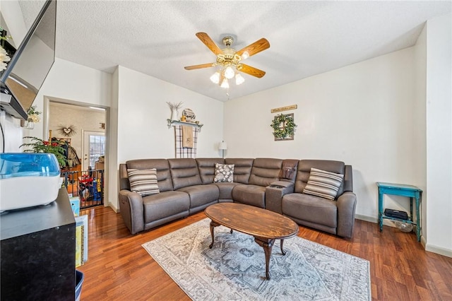 living room featuring baseboards, a textured ceiling, a ceiling fan, and wood finished floors