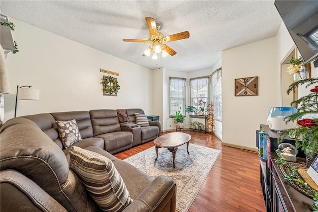 living area with baseboards, a textured ceiling, ceiling fan, and wood finished floors