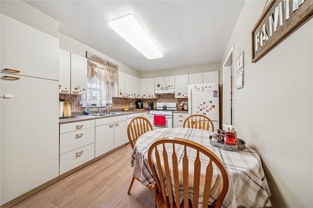 kitchen with white appliances, white cabinetry, and light wood-style floors