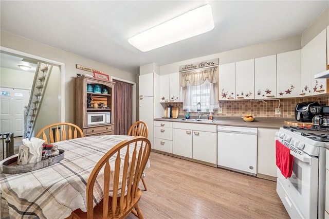 kitchen with white appliances, light wood-style floors, white cabinets, and tasteful backsplash