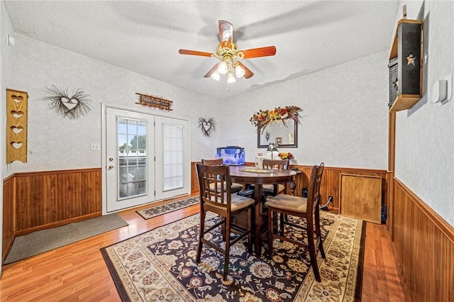 dining space with wainscoting, a textured ceiling, and wood finished floors