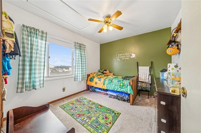 carpeted bedroom featuring baseboards, attic access, and a ceiling fan