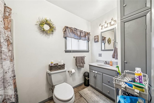 full bathroom featuring vanity, wood finished floors, baseboards, curtained shower, and toilet