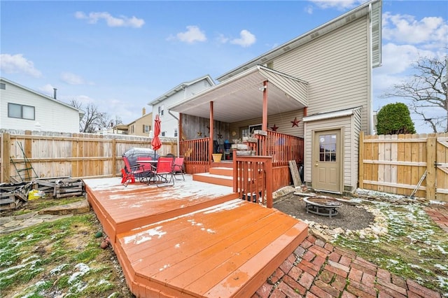 deck with outdoor dining area, a fire pit, and a fenced backyard