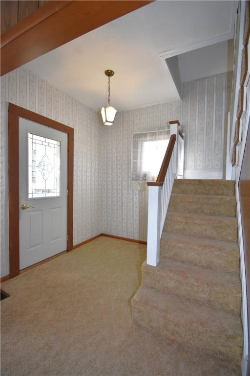 entrance foyer with wallpapered walls, stairs, carpet, and baseboards