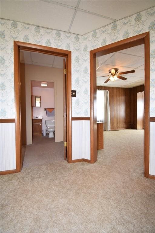 hallway featuring a wainscoted wall, wallpapered walls, and carpet floors