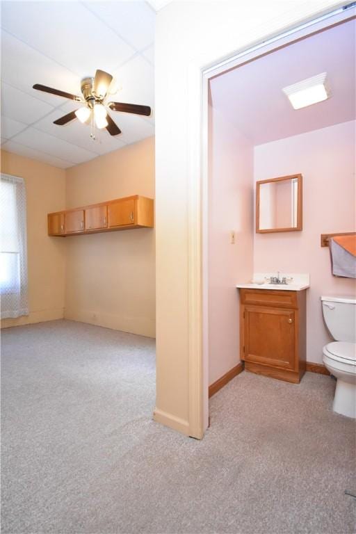 half bath with baseboards, toilet, vanity, and a ceiling fan