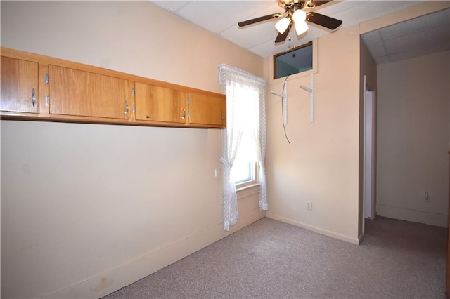 spare room featuring light colored carpet, baseboards, and ceiling fan