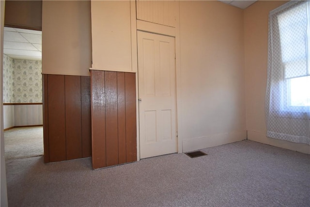 unfurnished bedroom featuring a drop ceiling, carpet flooring, and wallpapered walls