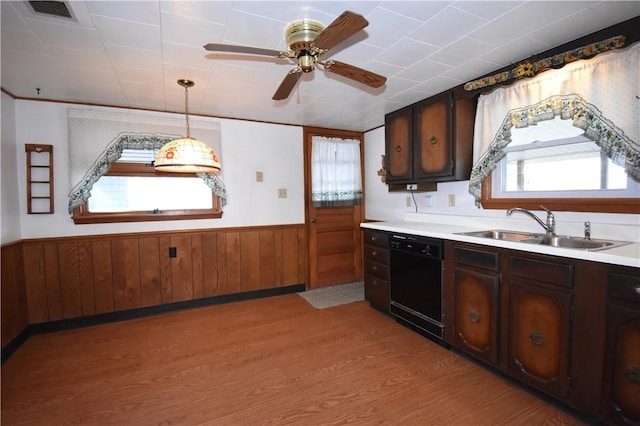 kitchen featuring a sink, light wood-style floors, wainscoting, light countertops, and dishwasher