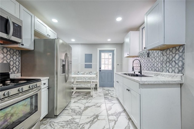 kitchen featuring light countertops, recessed lighting, appliances with stainless steel finishes, marble finish floor, and a sink