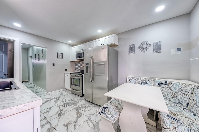 kitchen featuring marble finish floor, appliances with stainless steel finishes, white cabinets, and light countertops