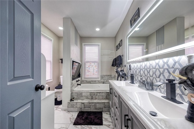 bathroom with a sink, marble finish floor, a bath, and double vanity